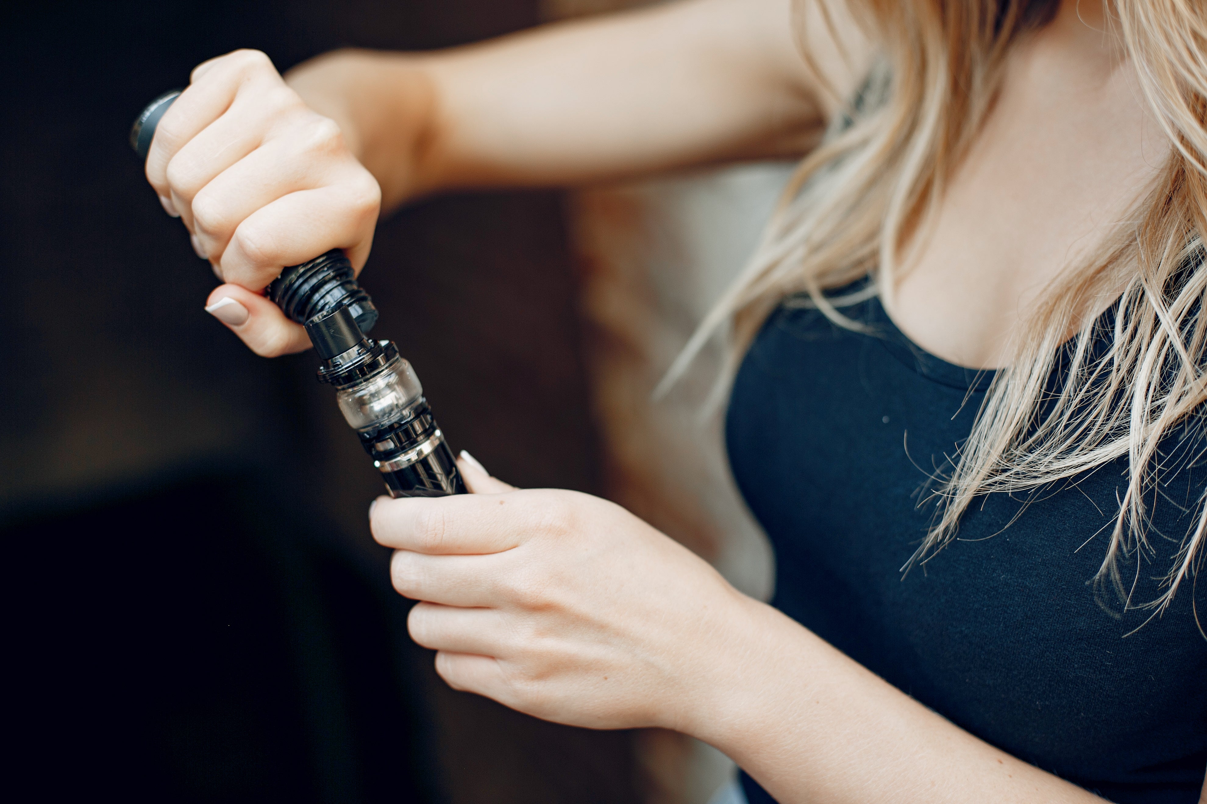 A woman putting vape juice in an empty cart
